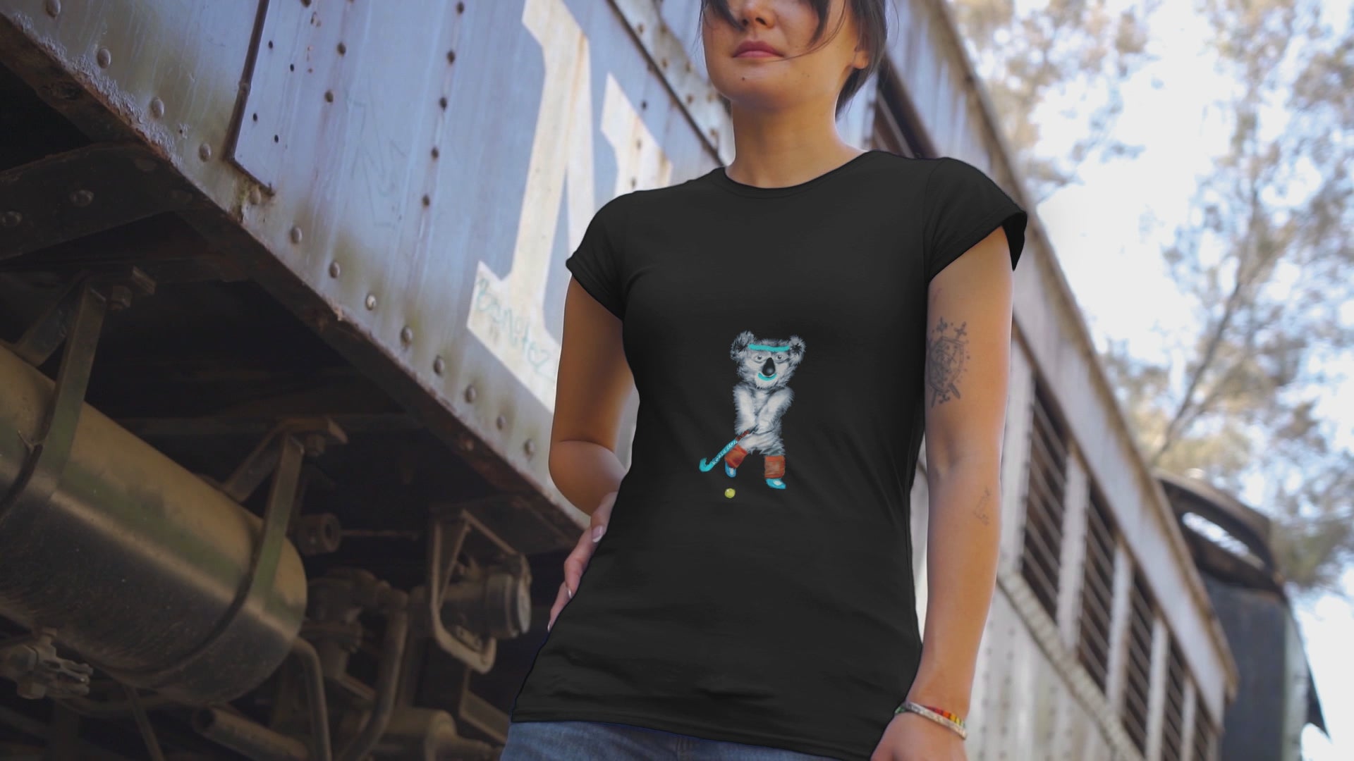 Koala playing hockey | 100% Organic Cotton T Shirt worn by a woman by a train