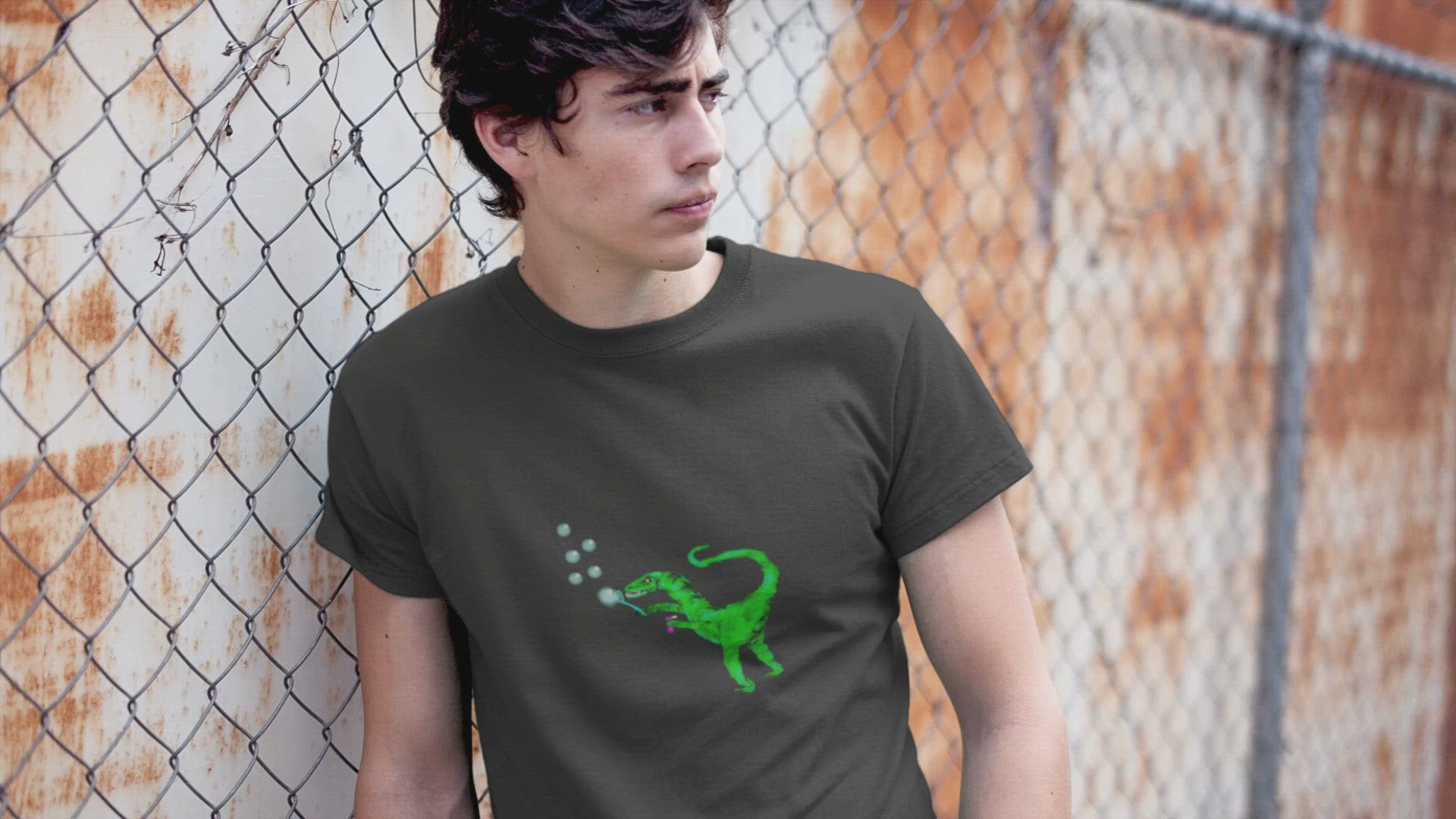 Dinosaur Velociraptor | Organic Cotton T Shirt worn by a man leaning by a fence