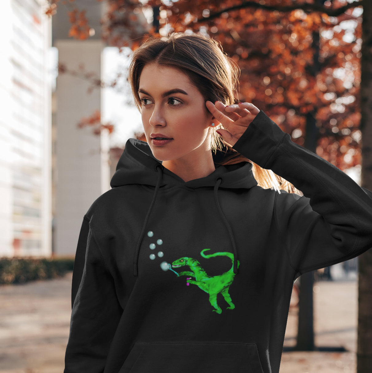 Woman wearing a Velociraptor blowing bubbles sustainable vegan hoodie